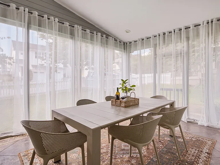 Indoor sun porch with dining table for 6, leading outside to the fenced-in yard.
