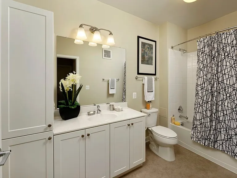 Bathroom with white shaker cabinetry, white countertop, shower and bath with white tile backsplash and hard surface flooring