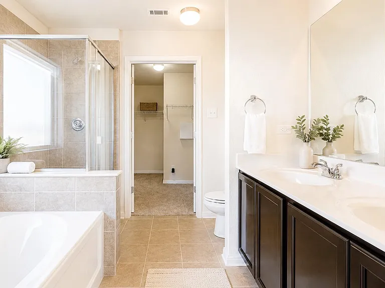 Spacious bathroom with dual-sink vanity, large soaking tub, and tiled walk-in shower plus a walk-in closet for storage.