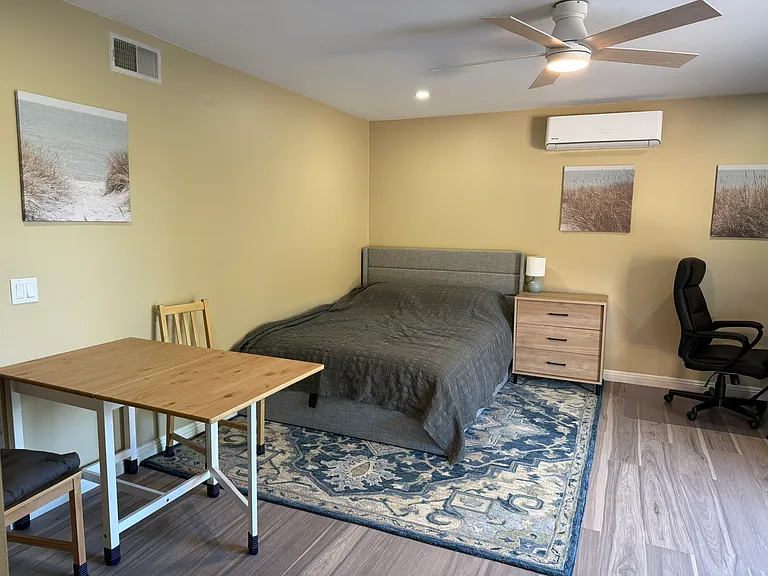 Living space includes mini-split, bed, dresser, and dining table with two chairs
