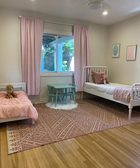 Second bedroom with large windows looking out to covered patio and ceiling fan