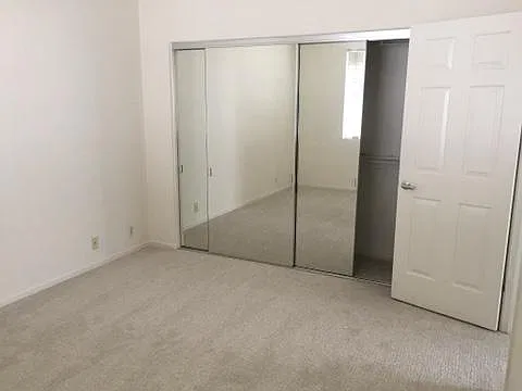 Bedroom with wall-length mirrored closet.