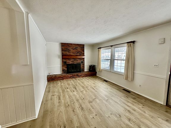 Living Room with Wood Burning Fireplace. New Mohawk Hybrid Resilient floors have been installed in the living room.