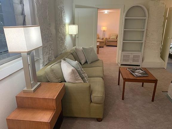 Comfortable living room with two side tables, lamps, coffee table and bookshelf.