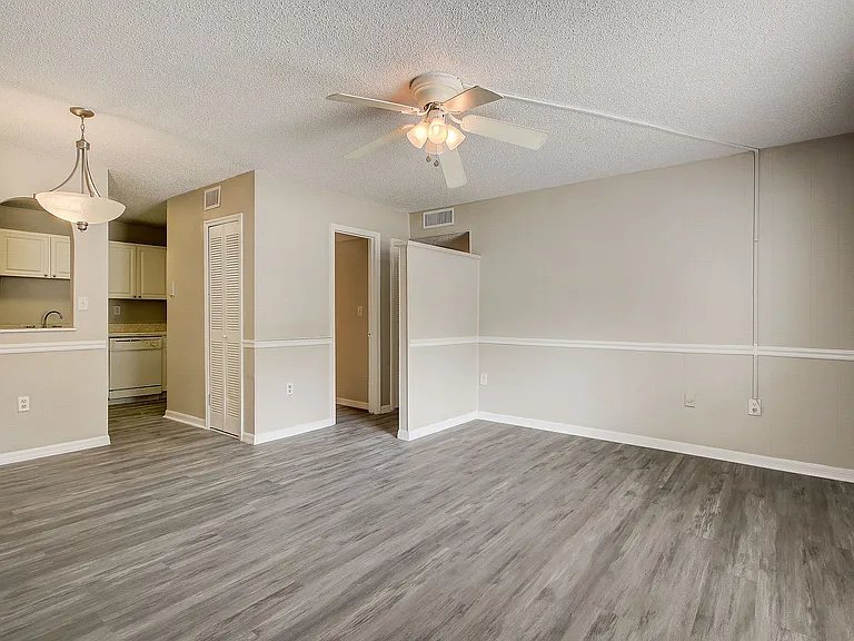 Chic apartment interior with modern laminate flooring, streamlined kitchen view, and elegant ceiling fan lighting.