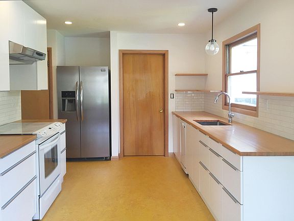 Updated kitchen with warm fir countertops, side-by-side refrigerator, and open shelving for personalization. Door to separate laundry room, which has interior access to the garage and then backyard.