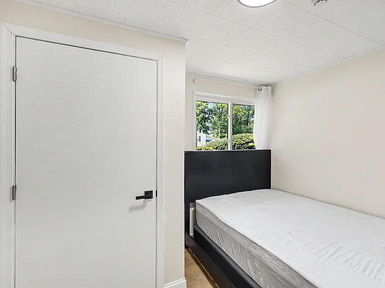 Private bedroom with a full-size bed, neutral finishes, and a window with curtain panels for natural light and privacy.