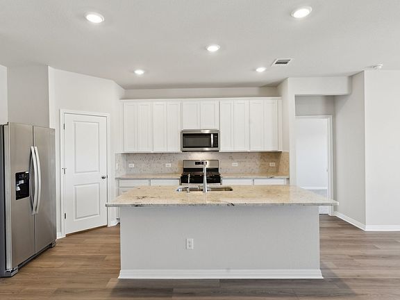 This kitchen features linen-colored cabinets and granite countertops.