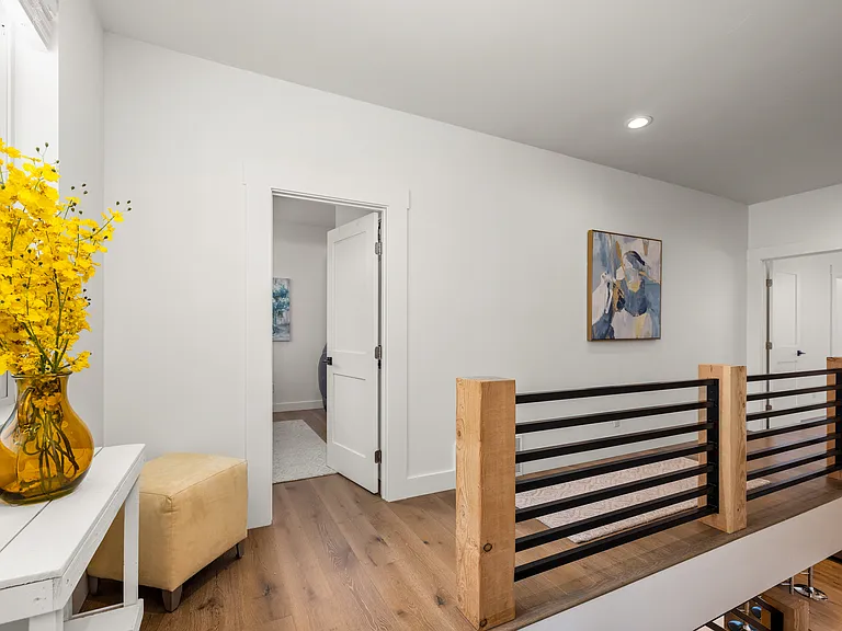 Spacious second-floor hallway connecting the bonus room, primary suite, additional bedrooms, and dedicated laundry room with a warm mountain-modern design throughout.