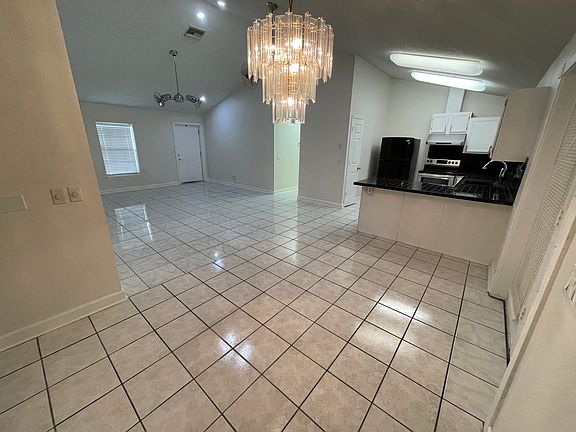 View of the kitchen and of the main entrance door from the dining area. To the right from the kitchen is a double door to the back patio.