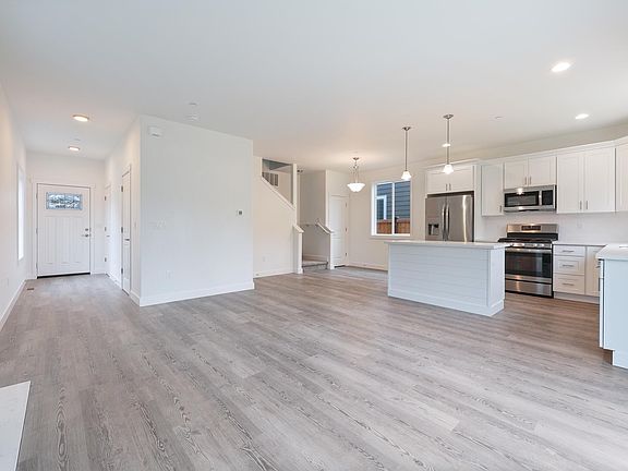 Great room from front entry on left to stairs to upper story in center and kitchen on right