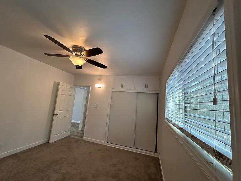 Bedroom with ceiling fan, natural light from window on the right