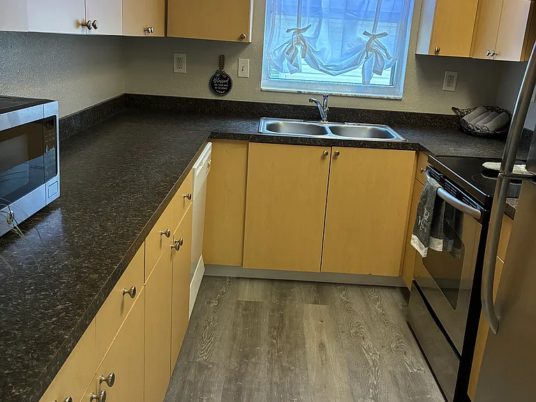 Stainless steel refrigerator, flat surface electric stove, and microwave.