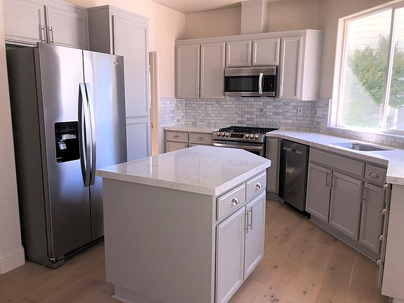 remodeled kitchen with newly painted cabinets, brushed nickel hardware, new stainless steel appliances, large stainless steel sink and quartz countertops