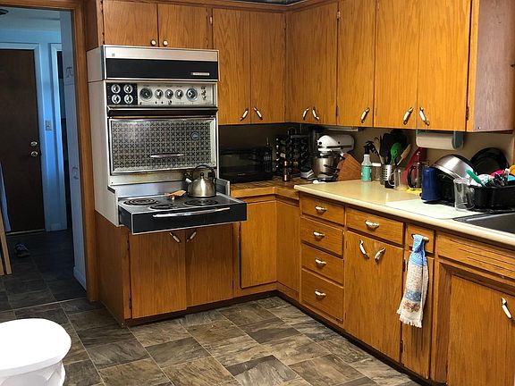 Kitchen looking from the dining room towards the laundry room and door to garage. There are some built in storage cabinets on the left wall (not visible in this photo). Refrigerator is to the right.
