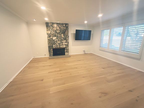 Spacious Living Room with natural stone firplace, plantation shutters and recessed lighting!