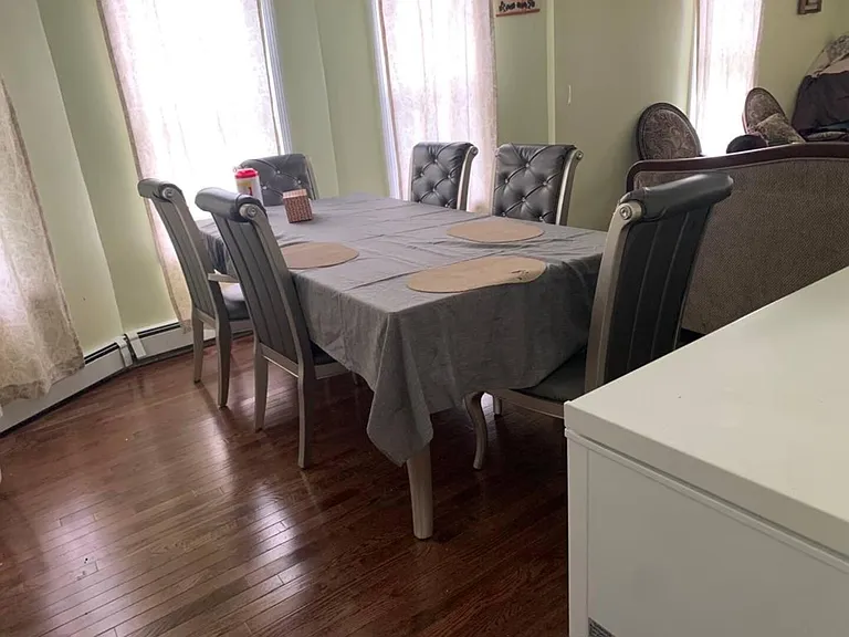 Dining area with a full-size table, upholstered seating, and adjacent windows for natural lightideal for shared meals.