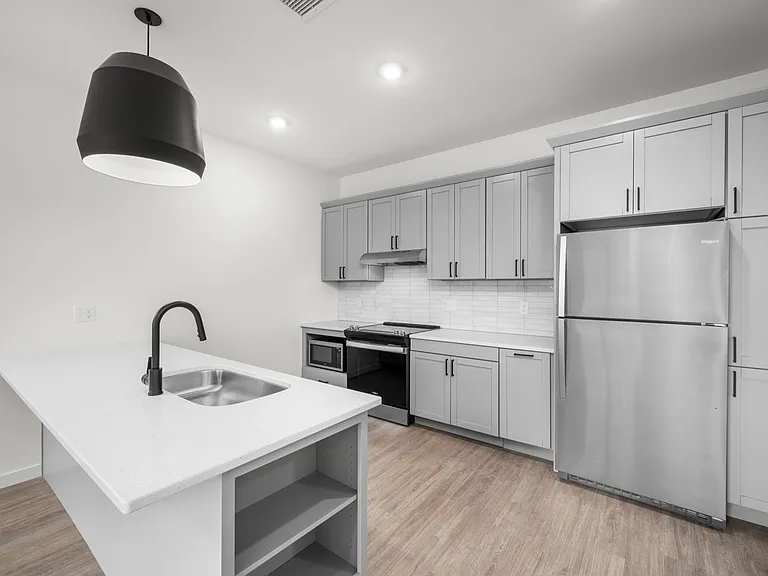 Modern kitchen with sleek grey cabinets, stainless steel appliances, and an elegant pendant light over a spacious white island. Modern kitchen with sleek grey cabinets, stainless steel appliances, and an elegant pendant light over a spacious white island.