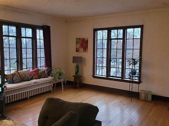 Spacious living room with large original windows and hardwood floors.