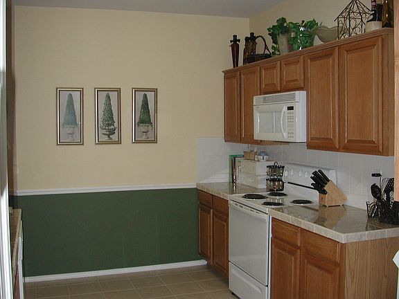 Bright kitchen has granite tile countertops and tile backsplash.