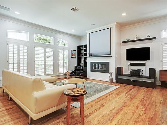 The expansive living area features high ceilings, large windows with plantation shutters, great natural light, a linear gas fireplace and gleaming hardwood floors.