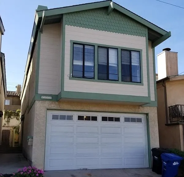 Street view of 2 car garage and 2nd story living room with ocean view.