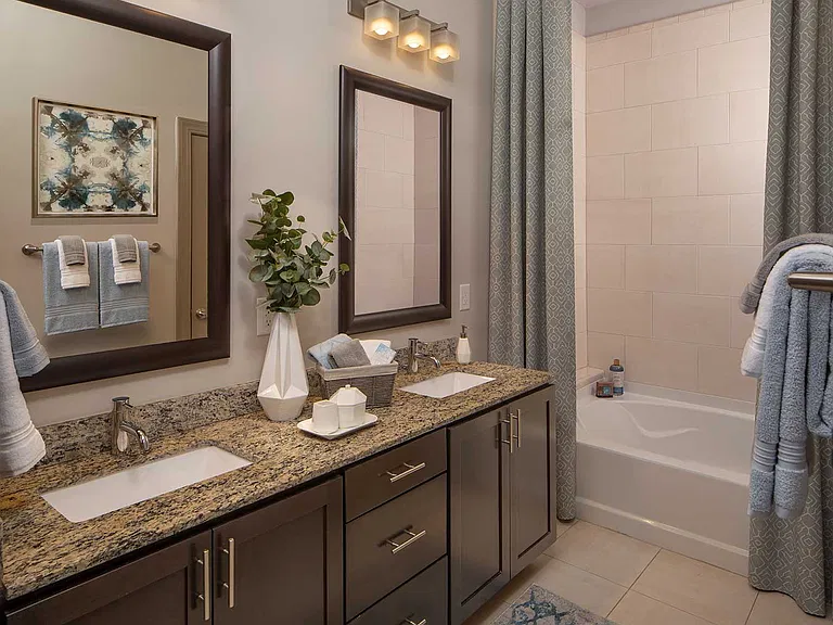alt="Bathroom with granite counters, double sinks, and shower/tub combo"