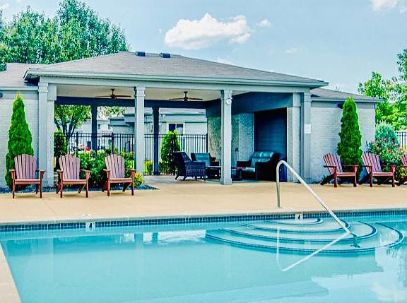 Pool Cabana complete with WIFI, ceiling fans along with patio poolside cushioned seating. Adirondack Chairs face the pool looking towards floating chairs in the shallow end.