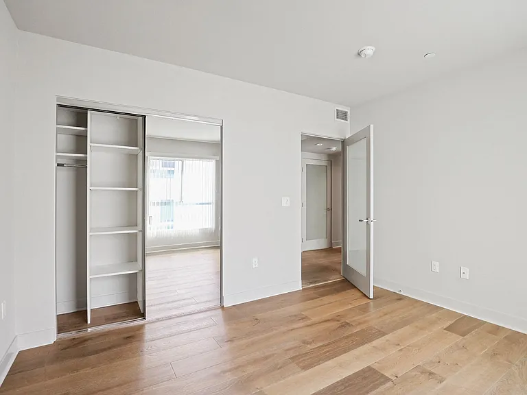 Bedroom with Mirrored Closet with Built-In Shelving and Vinyl Flooring