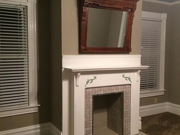 Decorative fireplace in living room with one-of-a-kind mantle mirror. New carpet. New blinds in the windows.