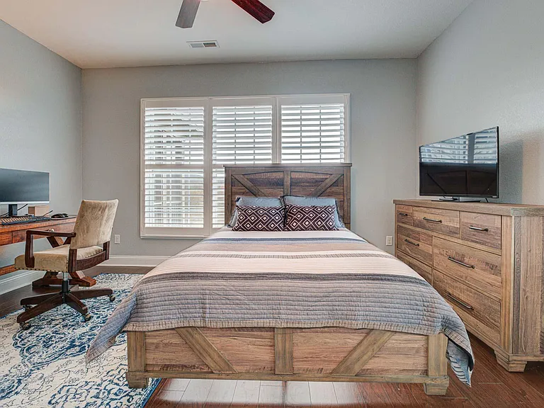 Guest bedroom 2 with queen bed, dresser and desk.