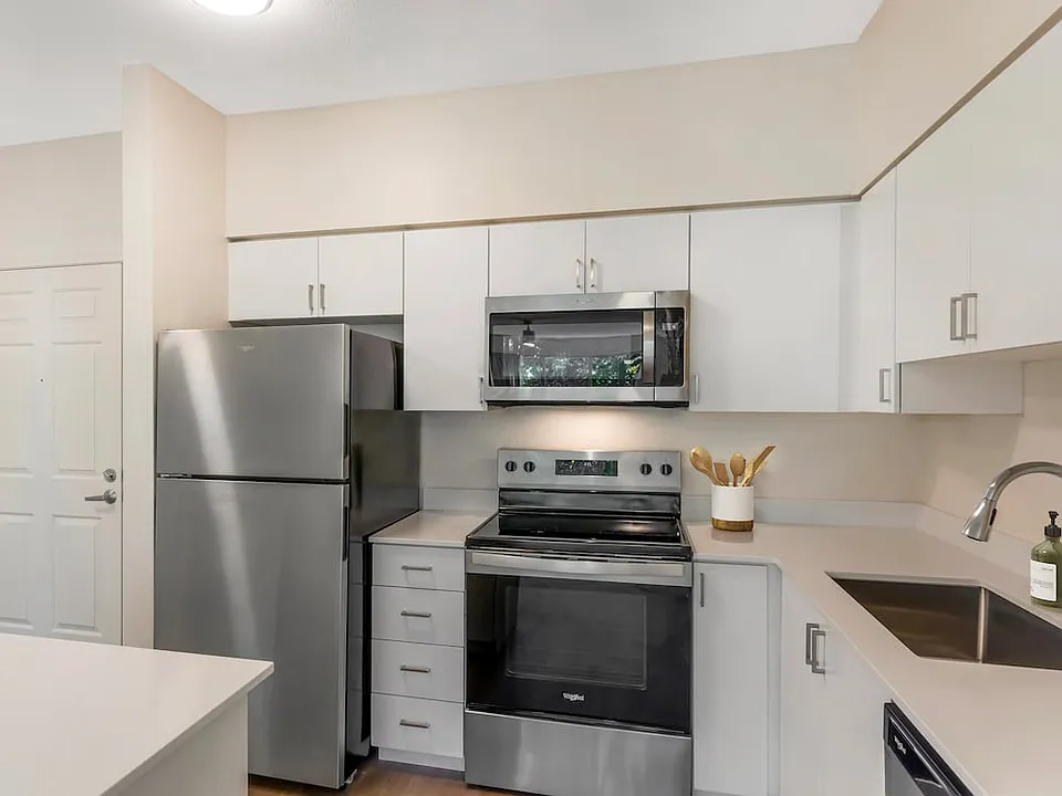 Renovated Package I kitchen with stainless steel appliances, white quartz countertops, white cabinetry, and hard surface flooring