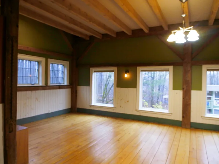 Huge living room with hardwood floors, lots of light and exposed beams.