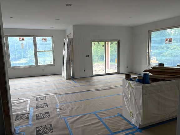 Inside view from kitchen island to dining area and great room, large windows to beautiful view in back, slider to deck... still under construction but ready in September!