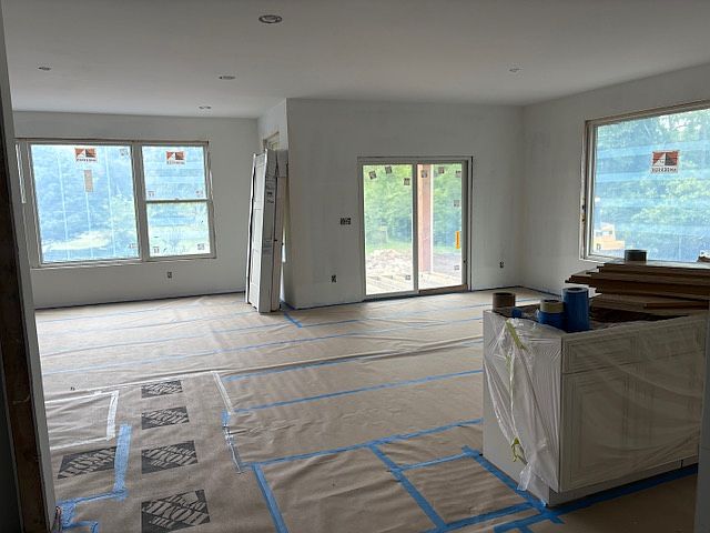 Inside view from kitchen island to dining area and great room, large windows to beautiful view in back, slider to deck... still under construction but ready in September!