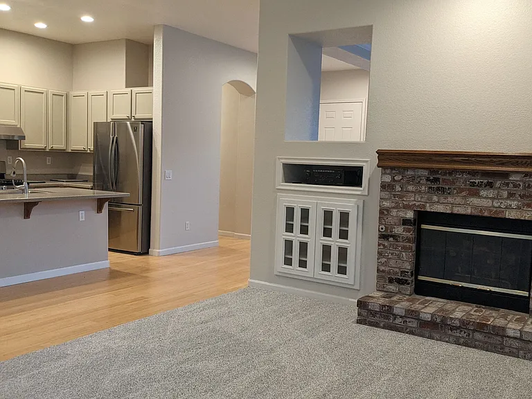 living room with fireplace and entertainment center, looking into the kitchen