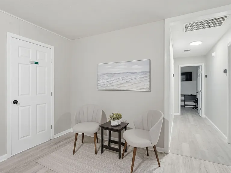 Neat seating nook off the hallway with two accent chairs and a side tableideal for reading or waiting space.