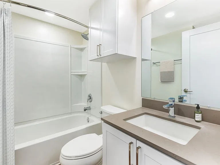 Renovated Package II bath with light grey quartz countertop, white shaker cabinetry, and hard surface flooring