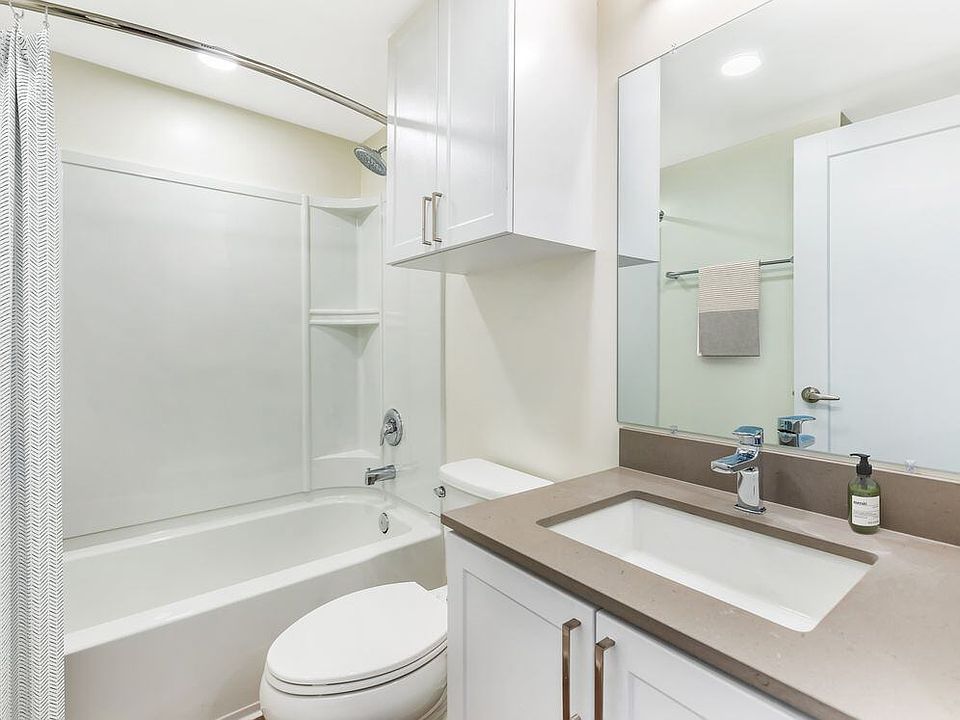 Renovated Package II bath with light grey quartz countertop, white shaker cabinetry, and hard surface flooring