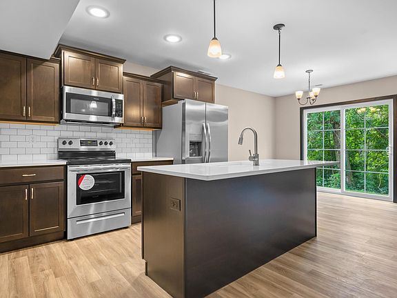 Kitchen with stainless steel appliances, farm-style sink, and large island. Beautiful quartz countertops and white subway tile backsplash.