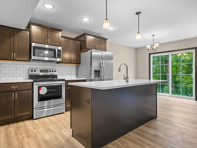 Kitchen with stainless steel appliances, farm-style sink, and large island. Beautiful quartz countertops and white subway tile backsplash.