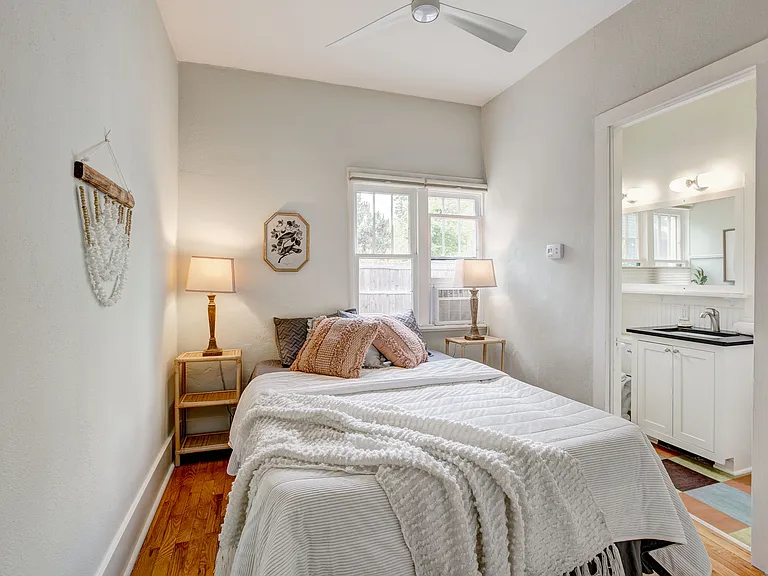 small bedroom with south facing windows holds queen sized bed