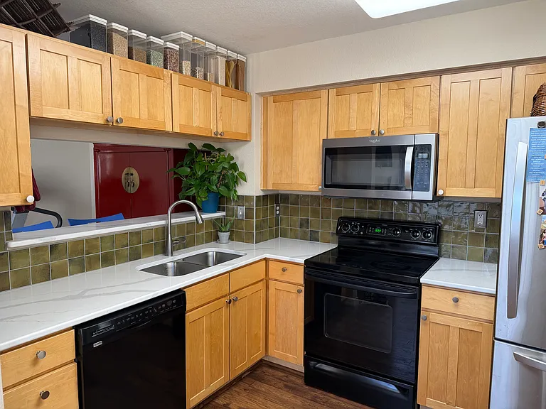 Kitchen with new quartz countertops, tile backsplash, sink, faucet and microwave. Large stainless steel fridge. Technically is the size of an "eat-in" kitchen.