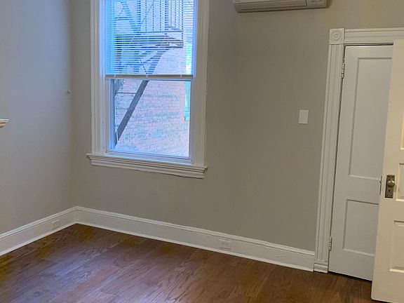 View of the bedroom from the back corner looking out the side window and the split level HVAC unit