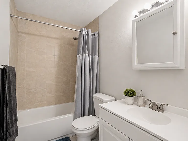 The bathroom is clean and modern, featuring a fully tiled shower, updated fixtures, and a bright, functional layout designed for everyday comfort