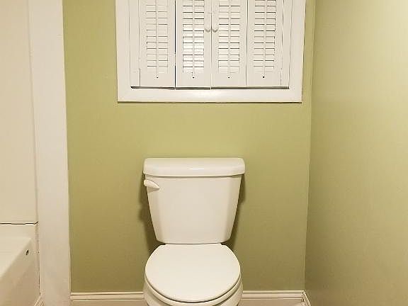 Bathroom toilet, with storage cabinet below window
