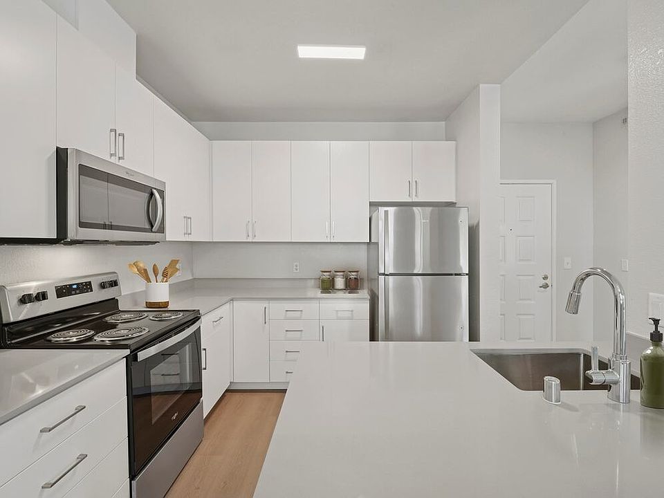 Renovated Package I kitchen with white cabinetry, grey quartz countertops, stainless steel appliances, and hard surface flooring