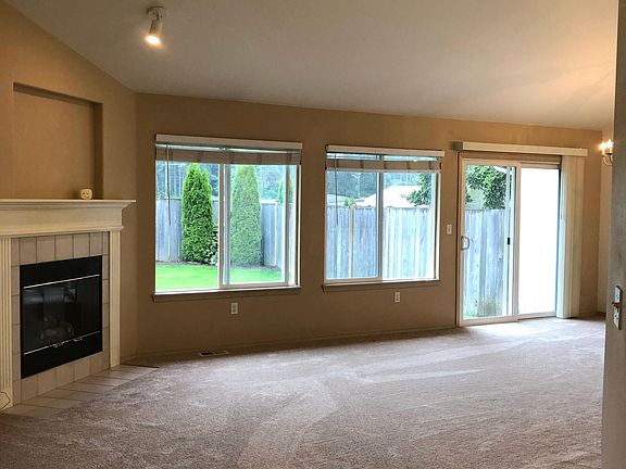 Spacious living room with gas fireplace facing the beautiful green backyard