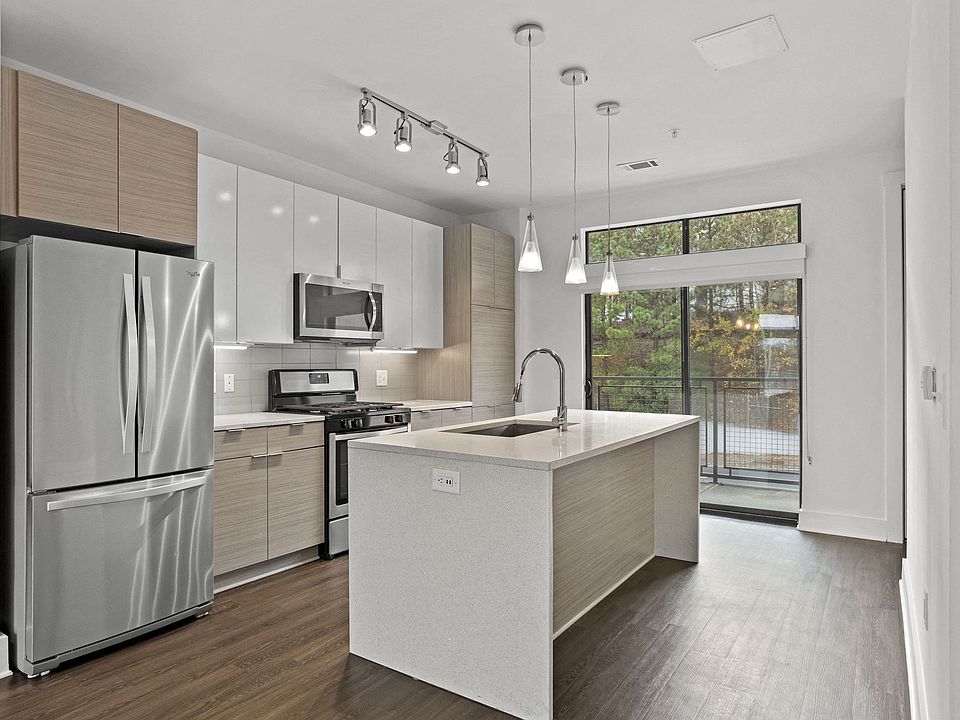Stainless steel appliances, gas range, pendant lighting, and an island with space for bar stools
