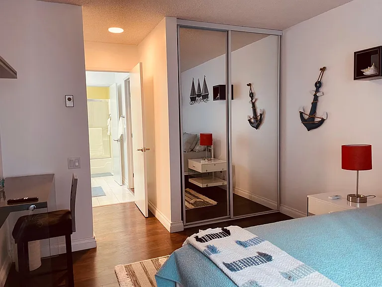 Second bedroom suite with en-suite bathroom, desk, large screen smart TV and two mirrored door closets